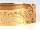 an image of a close up of a gold bracelet on a white surface