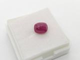 a close up of a red ruby stone on a white surface