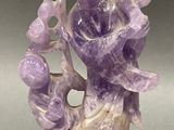 lavender quartzite sculpture on wooden base on grey background