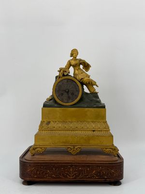 a gold clock with a statue on top of it