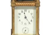 une horloge dorée avec un cadran blanc sur fond blanc