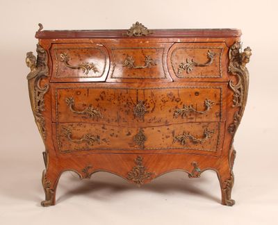 une commode ancienne ornée de sculptures élaborées sur le dessus