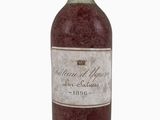 une vieille bouteille de vin posée sur une surface blanche