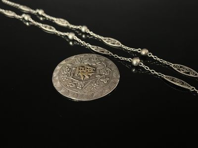 a close up of a silver coin with a chain around it
