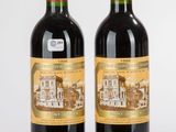 deux bouteilles de vin rouge posées l'une à côté de l'autre sur une surface blanche
