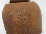 an old rusty bell hanging on a white wall