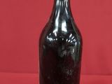 bottle of black wine on a red surface with a red background