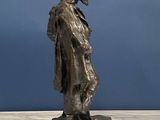 statue of a man in a hat and coat standing on a marble base