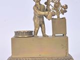 figurine en laiton représentant un garçon tenant une plante en pot, posée sur un socle
