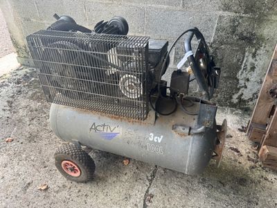 un petit compresseur d'air posé par terre près d'un mur