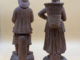 two figurines of people standing next to each other on a table