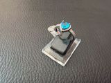a silver ring with a blue stone on top of a cell phone
