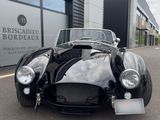 an old black sports car parked in front of a building