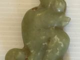 une statue verte représentant une grenouille assise sur une surface blanche