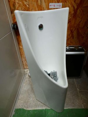 a urinal in the corner of a bathroom with a green floor