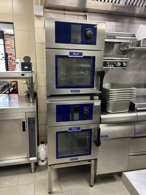 Dans une cuisine, plusieurs fours en acier inoxydable sont empilés les uns sur les autres.