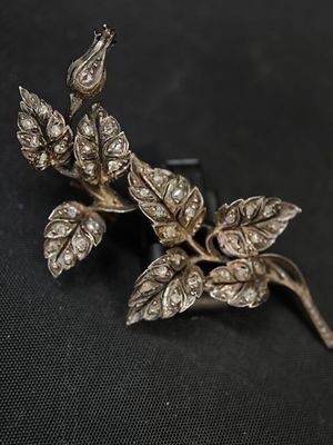 une broche en argent ornée de feuilles sur un fond noir