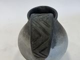 a black vase sitting on a table with a white background