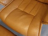 a brown leather chair and ottoman in a room
