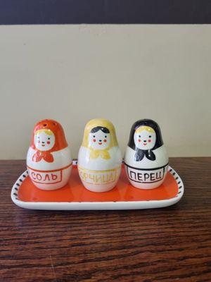 three salt and pepper shakers on a tray on a table