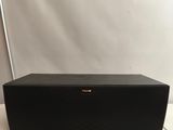 a black speaker sitting on top of a table next to a white wall