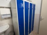 une salle de bains équipée de casiers bleus et d'un lavabo