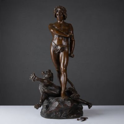 une statue en bronze représentant un homme avec un chien, assis sur un rocher