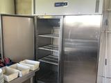 un grand réfrigérateur en acier inoxydable dans une cuisine où il y a beaucoup de vaisselle sur le plan de travail