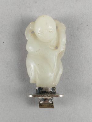 une image représentant une statuette en jade blanc posée sur un socle en argent