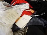 a pile of clothes and a book on a bed