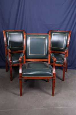 trois fauteuils en cuir vert et un fauteuil à structure en bois