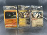 Trois cartes Pokémon sont posées sur une table