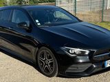 the black mercedes cla is parked on the side of the road