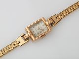 an image of a gold wrist watch with a chain around it