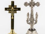 two silver and gold crosses sitting next to each other on a white surface