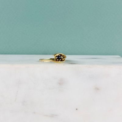 un gros plan d'une bague en or sertie d'un diamant noir, posée sur un bloc de marbre