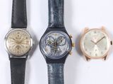 three different watches sitting next to each other on a white surface