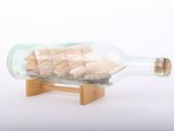 a small ship in a glass bottle on a wooden stand