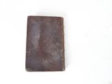 an old brown leather book sitting on top of a white table