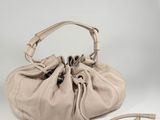a beige leather bag with a drawsack on the handle