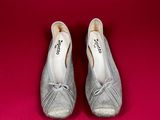 pair of women ' s silver shoes on a red background