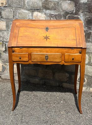a small wooden desk with a drawer on it in front of a stone wall