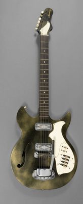 une image représentant une guitare métallique posée sur une surface grise