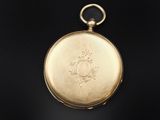 an antique gold pocket watch with a chain on a black background