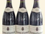 three bottles of red wine are lined up on a white surface