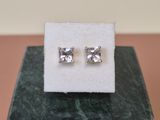 a pair of earrings sitting on top of a marble block