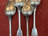 four silver spoons sitting on top of a red surface