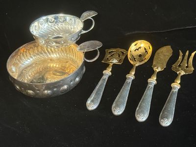 cinq cuillères en argent et un bol en argent posés sur une table noire