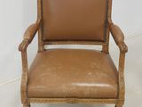 an old chair with a brown leather seat and a wooden frame