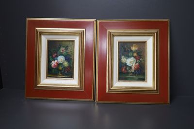 deux tableaux encadrés représentant des fleurs, posés sur une table dans une pièce